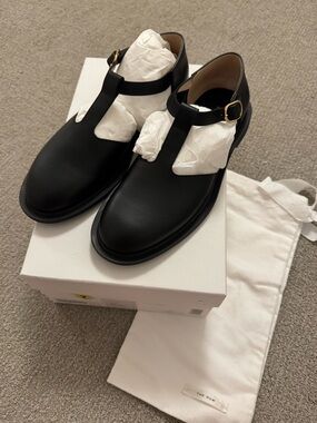 The Row Black Leather Nic T-Strap Loafers with Gold Buckle